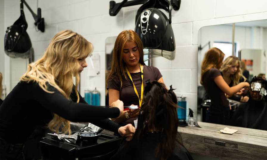 Two students styling another students hair