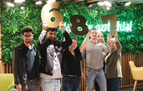 Students standing in front of green neon sign say you've got this. Students holding gold numbers 6, 7 and 8.