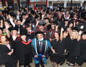 large group of graduates waving and smiling to camera