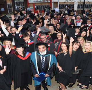 large group of graduates waving and smiling to camera
