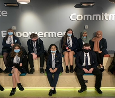 group of school pupils sat on benches some wearing face masks