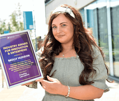 Molly Hudson smiling to camera holding certificate for Industry Award for Innovation & Enterprise